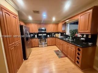 A kitchen features wood cabinets, black countertops, stainless steel appliances, and light wood flooring — 16236 SW 100th Ter, Miami FL 33196, MIAMI, FL