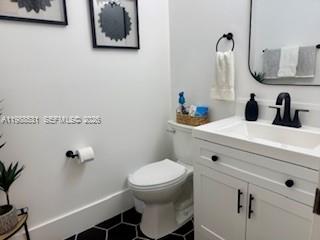 A small bathroom features a white vanity, a toilet, and black hexagonal floor tiles — 16236 SW 100th Ter, Miami FL 33196, MIAMI, FL