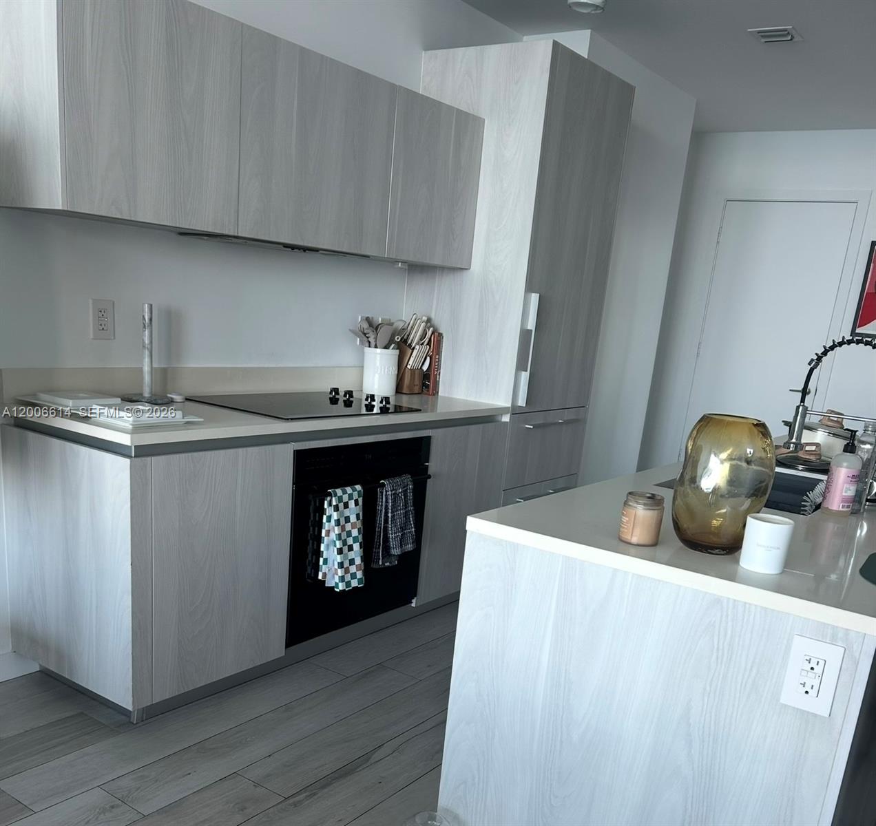 A modern kitchen features light wood-grain cabinets, white countertops, and a central island — 480 NE 31st St # 905, Miami FL 33137, MIAMI, FL