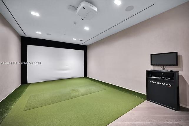 This indoor golf simulator room features a projector, a large screen, and artificial turf flooring — 480 NE 31st St # 905, Miami FL 33137, MIAMI, FL