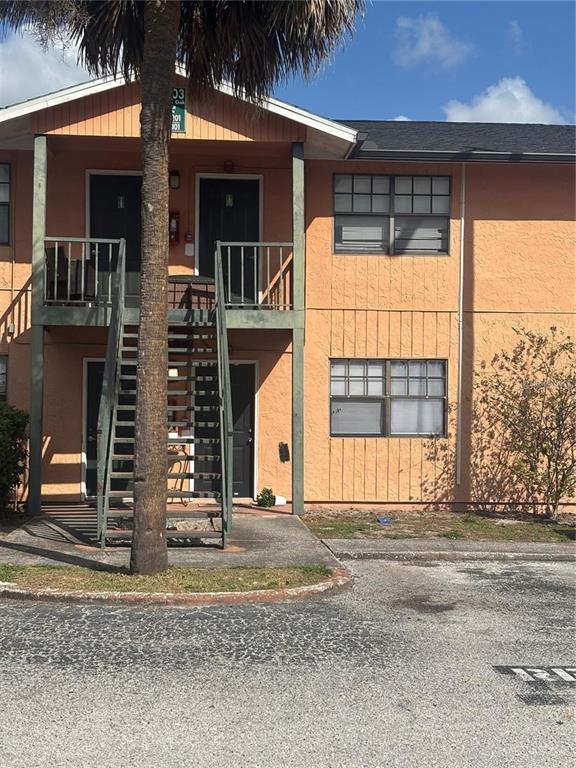 A two-story peach-colored apartment building features an exterior staircase leading to an upper balcony — 12403 HIBISCUS OAK PLACE UNIT 202, TAMPA, FL