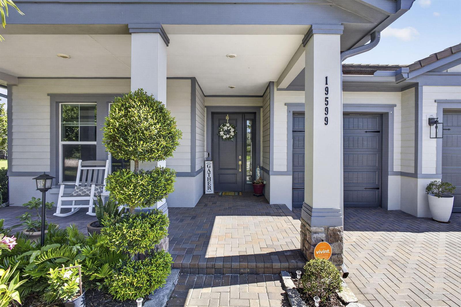 A front porch with a gray door, a topiary, and a brick walkway — 19599 Split Rail Run, Loxahatchee FL 33470, LOXAHATCHEE, FL