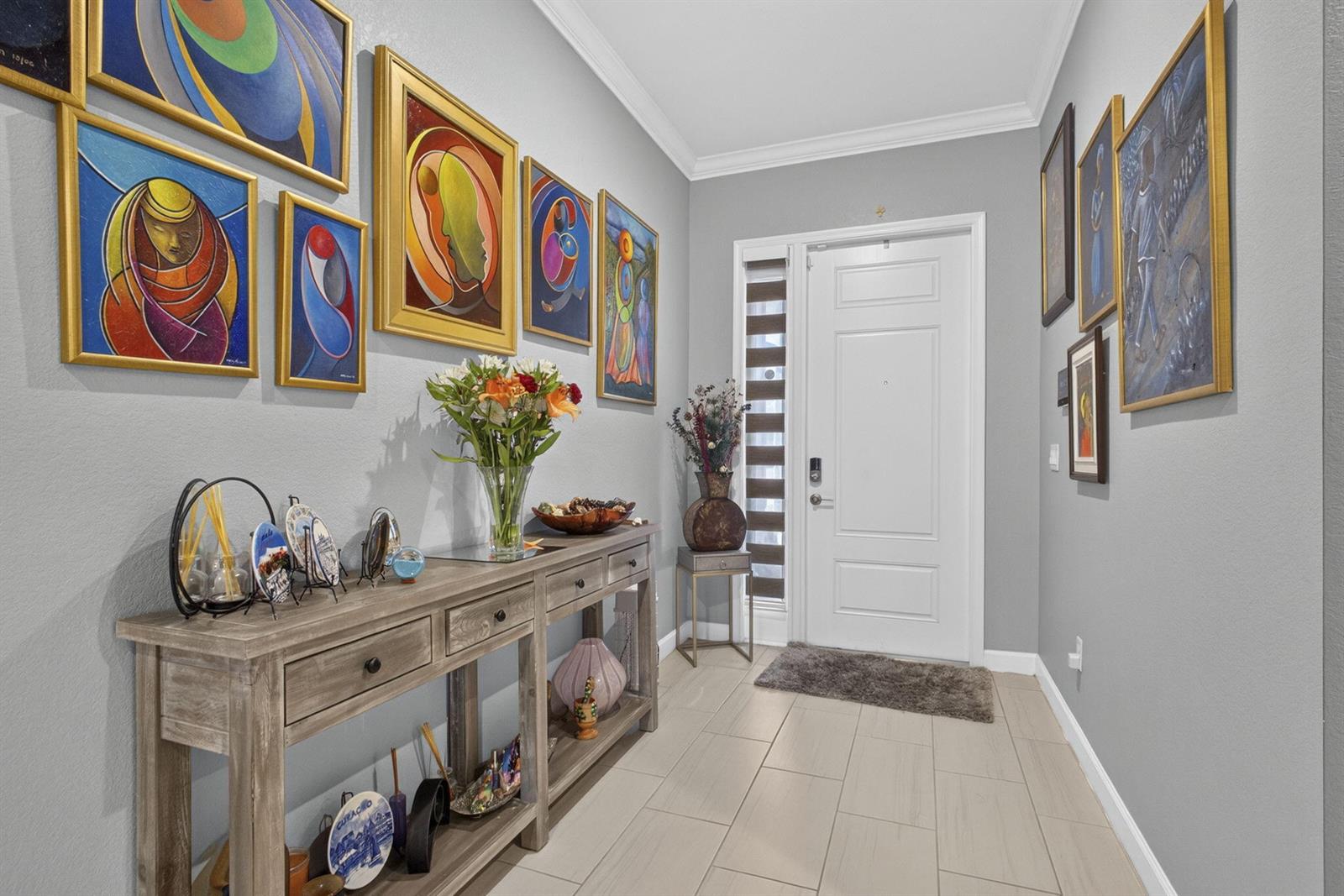 An entryway features a wooden console table, framed artwork on gray walls, and tile flooring — 19599 Split Rail Run, Loxahatchee FL 33470, LOXAHATCHEE, FL