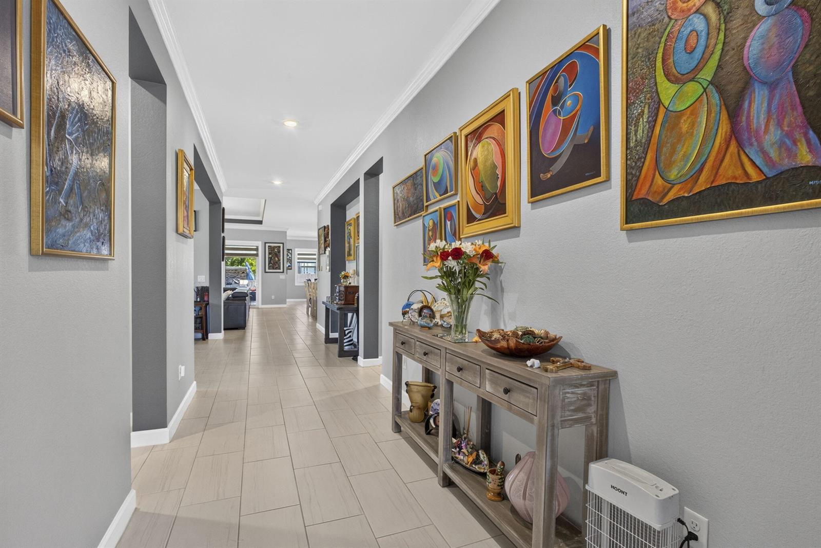 A long hallway features tiled floors, a wooden console table, and multiple framed abstract paintings — 19599 Split Rail Run, Loxahatchee FL 33470, LOXAHATCHEE, FL