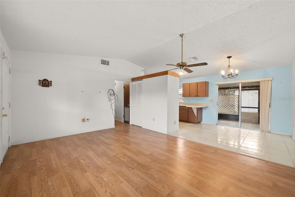 A living room with wood-look flooring transitions to a tiled kitchen area with a ceiling fan — 2067 N TERRAPIN ROAD, AVON PARK, FL