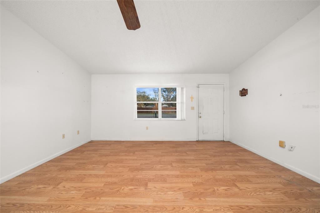 An empty room with white walls, wood-look flooring, a window, and a white entry door — 2067 N TERRAPIN ROAD, AVON PARK, FL