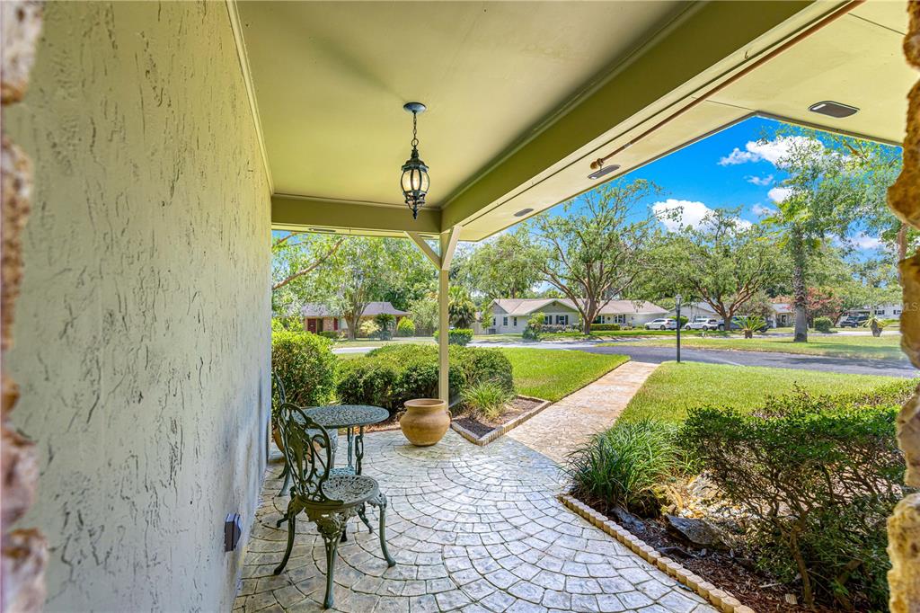 A covered patio features a stone-patterned floor, a small bistro set, and a hanging lantern — 3963 SE 15TH STREET, OCALA, FL