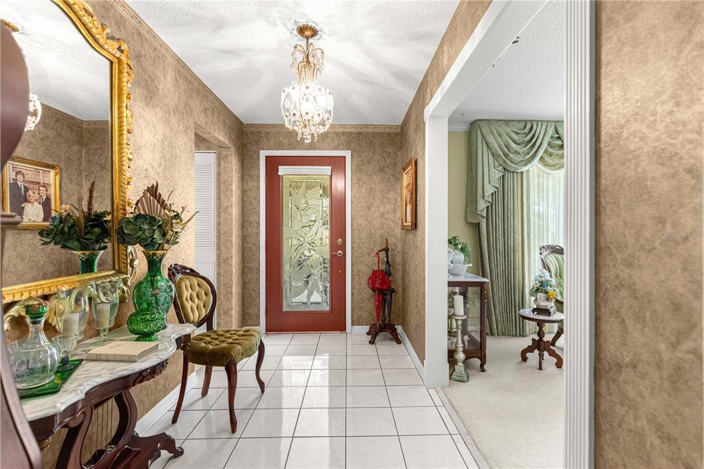 An entryway features a red front door, tiled floors, a chandelier, and a console table — 3963 SE 15TH STREET, OCALA, FL