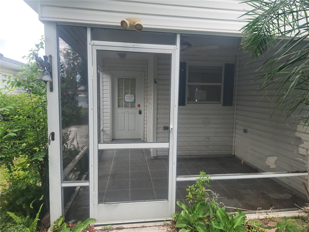 A screened-in porch features a white door, tiled flooring, and white horizontal siding — 17449 SE 81ST NEWBERRY COURT, THE VILLAGES, FL