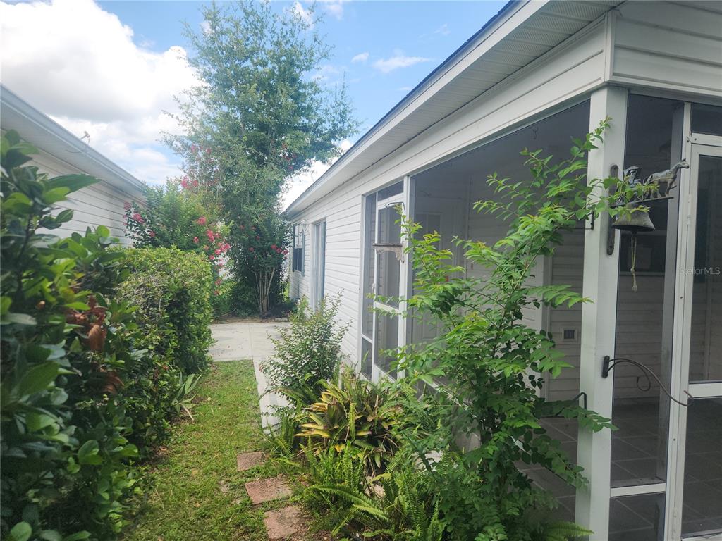 A side view of a house exterior featuring a screened porch and landscaped yard — 17449 SE 81ST NEWBERRY COURT, THE VILLAGES, FL
