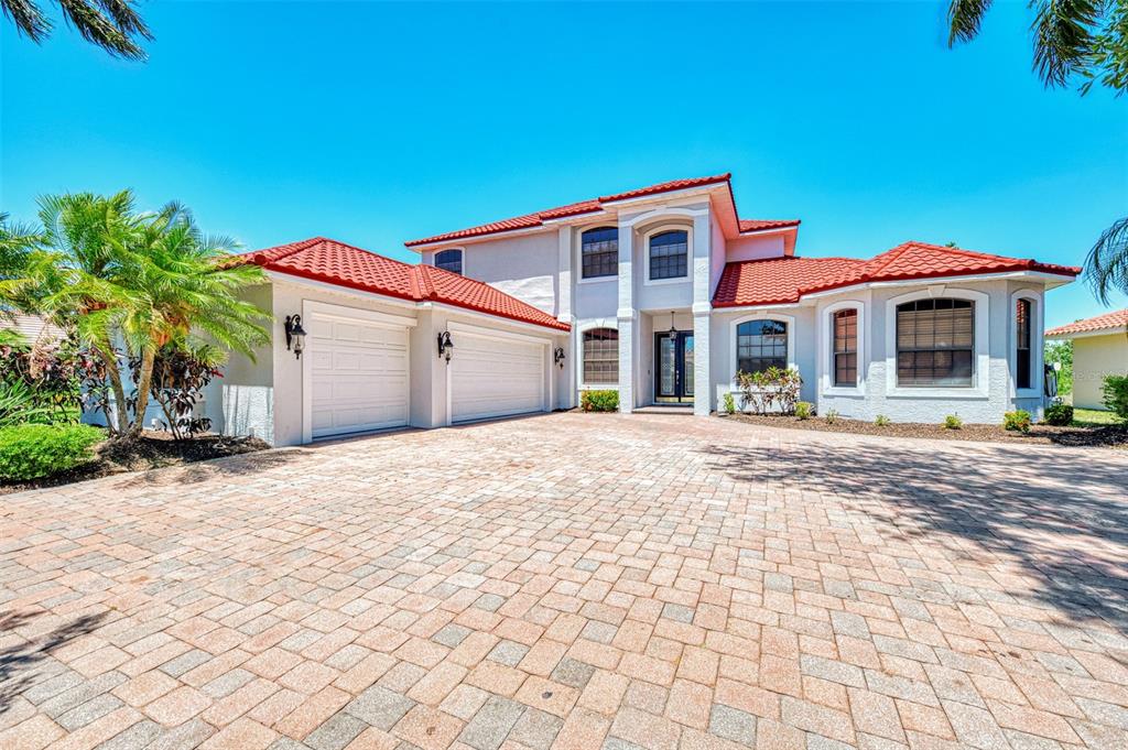A two-story house with a red tile roof, white stucco walls, and a paved driveway — 5684 EASTWIND DRIVE, SARASOTA, FL