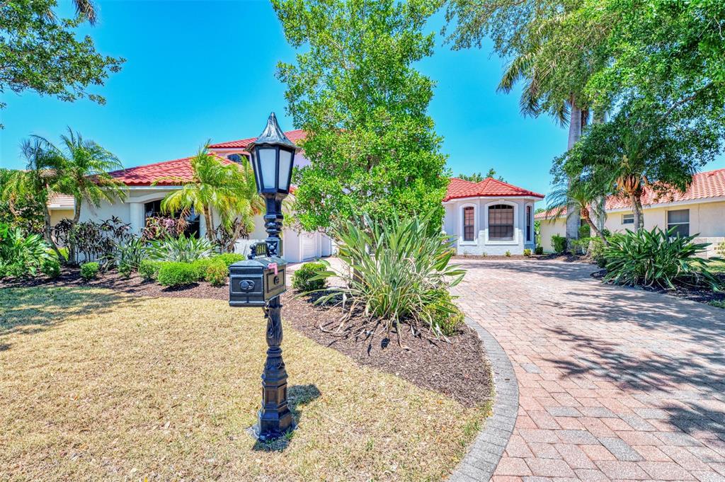 A black decorative mailbox and lamp post stand in front of a house with red tiles — 5684 EASTWIND DRIVE, SARASOTA, FL