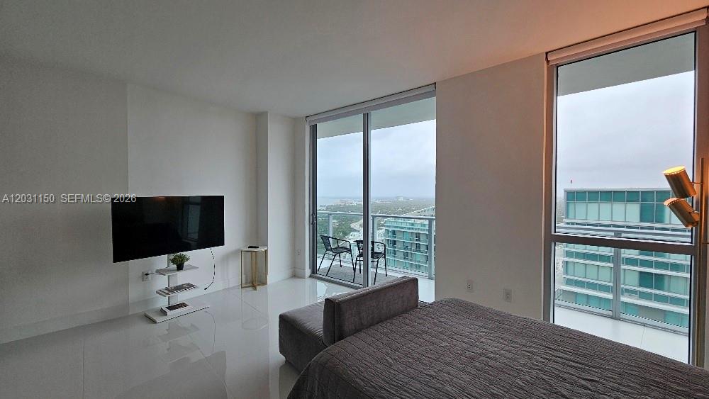 A bedroom features white tile floors, a television on a stand, and floor-to-ceiling windows — 1100 S Miami Ave # 4105, Miami FL 33130, MIAMI, FL