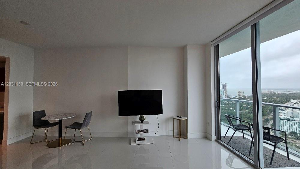 A modern living room features a dining set, a television on a stand, and a balcony — 1100 S Miami Ave # 4105, Miami FL 33130, MIAMI, FL