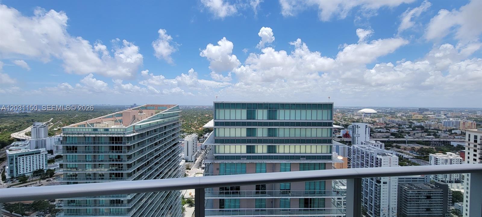 A high-angle view from a balcony overlooking several modern apartment buildings and a city skyline — 1100 S Miami Ave # 4105, Miami FL 33130, MIAMI, FL