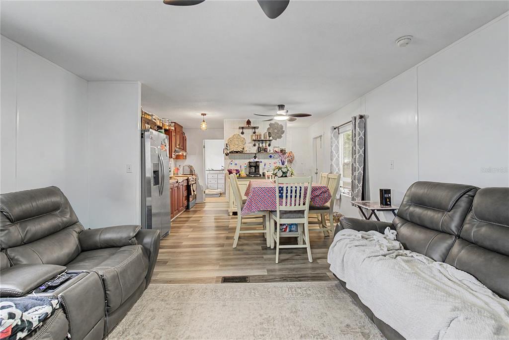 A living room with gray leather sofas opens into a dining area and kitchen — 935 S CRYSTAL GROVE POINT, HOMOSASSA, FL