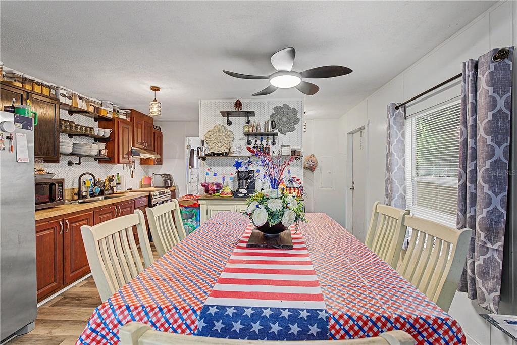 A dining area features a patriotic-themed tablecloth, wooden cabinets, and an overhead ceiling fan — 935 S CRYSTAL GROVE POINT, HOMOSASSA, FL