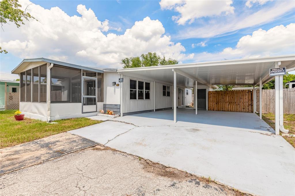 A single-story mobile home features a screened-in porch and a large attached metal carport — 103 ALOHA TERRACE, PORT ORANGE, FL