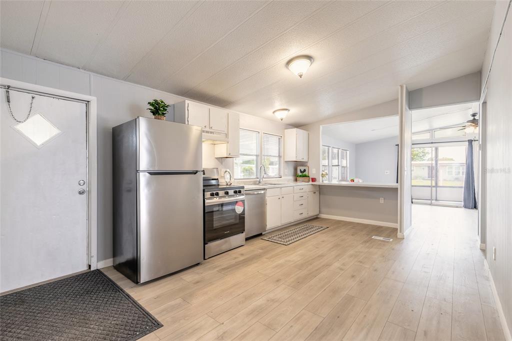 A kitchen with stainless steel appliances, white cabinets, and light wood-look flooring — 103 ALOHA TERRACE, PORT ORANGE, FL