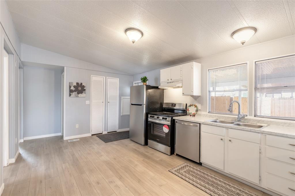 A kitchen with light wood-look flooring, white cabinets, stainless steel appliances, and two ceiling lights — 103 ALOHA TERRACE, PORT ORANGE, FL