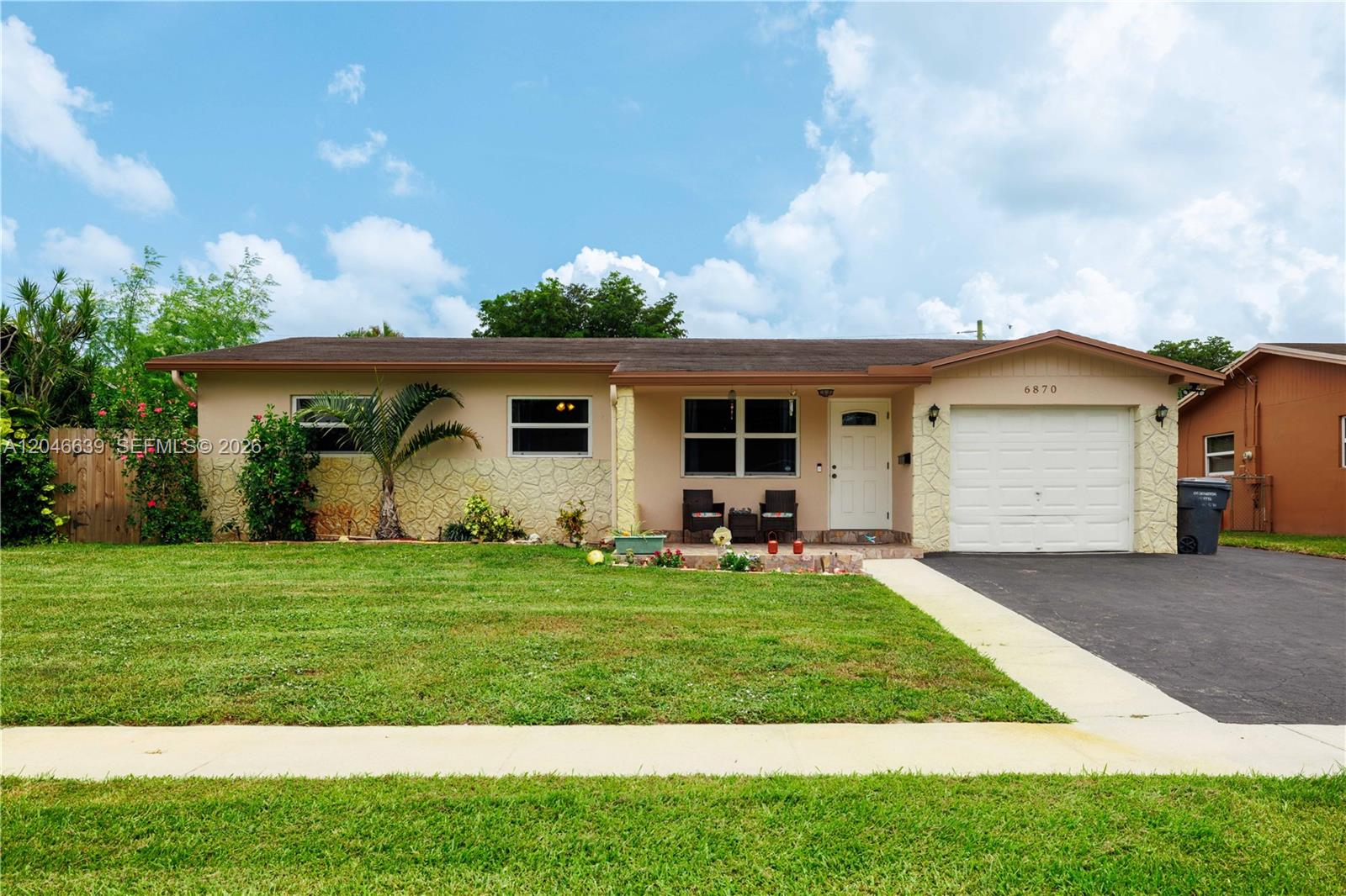 A single-story house with a beige facade, stone accents, a garage, and a front lawn — 6870 Pershing St, Hollywood FL 33024, HOLLYWOOD, FL