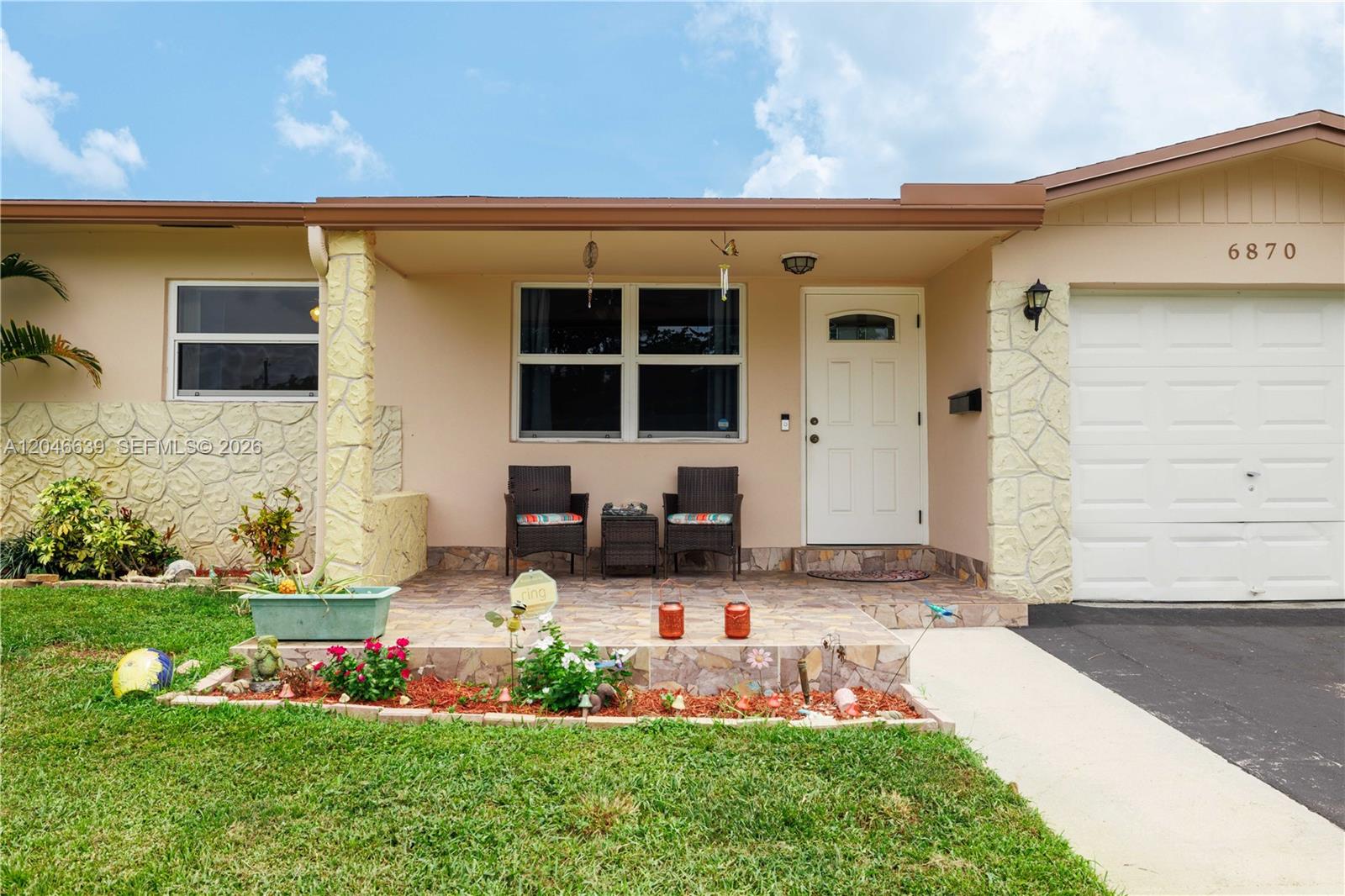 The exterior of a single-story house features a covered porch, stone accents, and a garage — 6870 Pershing St, Hollywood FL 33024, HOLLYWOOD, FL