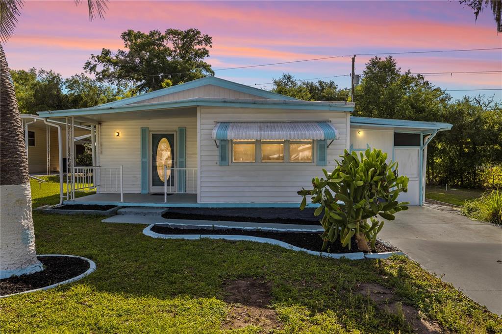 A single-story white house with light blue trim, a front porch, and a cactus garden — 6123 RIDGEWOOD DRIVE, ZEPHYRHILLS, FL