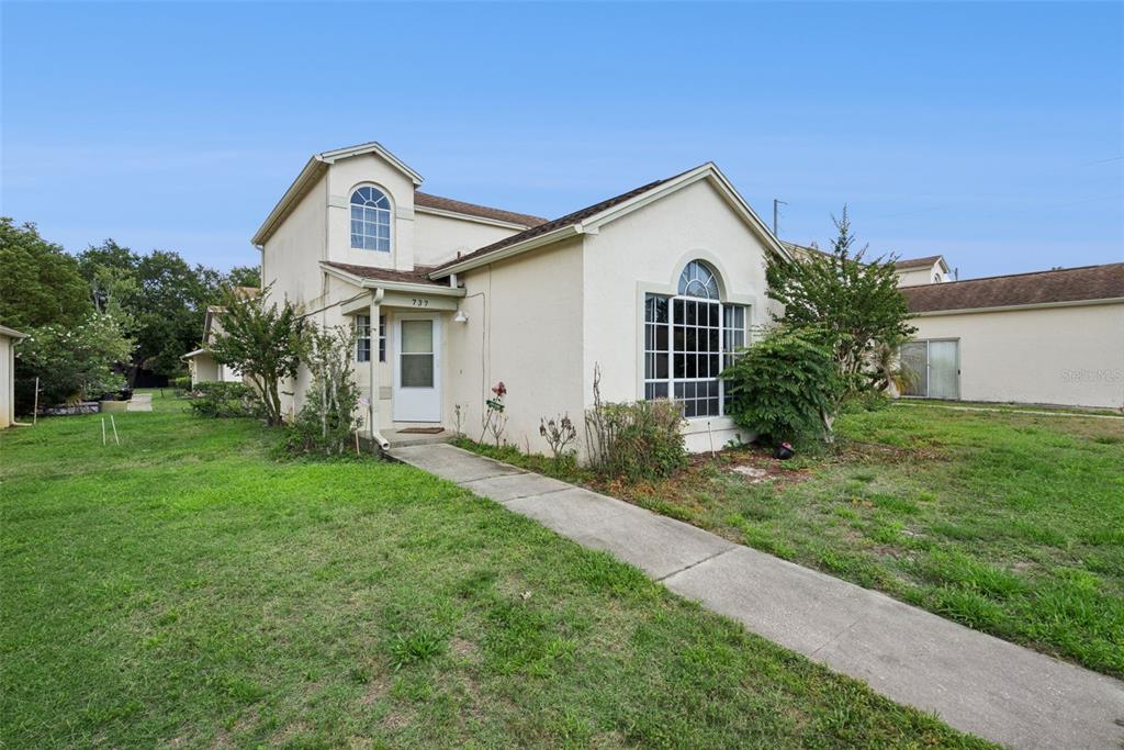A two-story house with a white stucco exterior, arched windows, and a concrete walkway — 737 OLYMPIC CIRCLE, OCOEE, FL