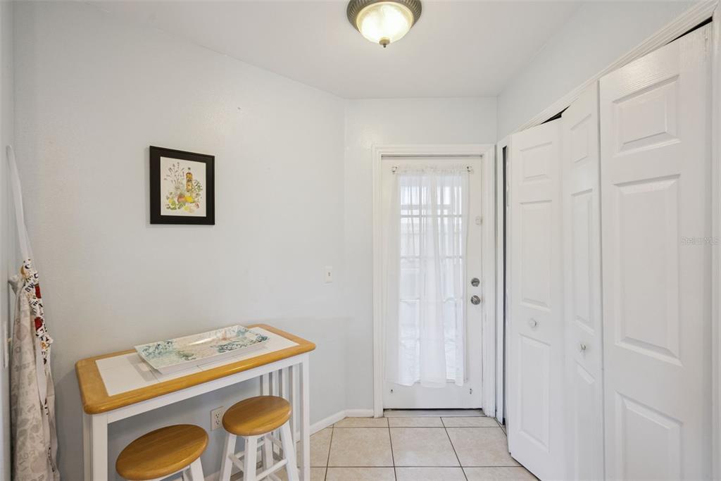 A small dining area features a tiled table, two stools, a door, and white closets — 737 OLYMPIC CIRCLE, OCOEE, FL