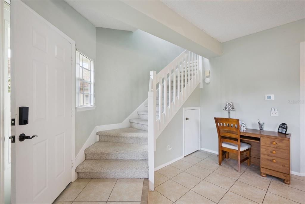 An entryway features a carpeted staircase, tile flooring, and a small wooden desk — 737 OLYMPIC CIRCLE, OCOEE, FL