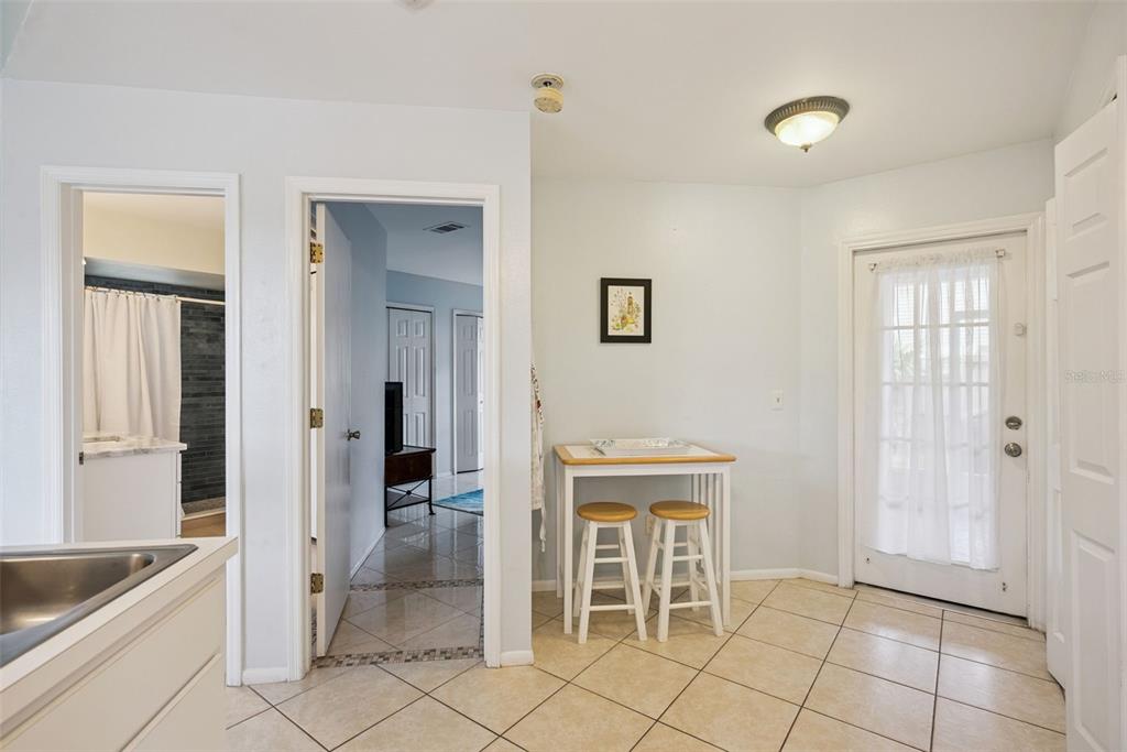 A kitchen area with tile floors, a small breakfast table, and a glass-paneled exterior door — 737 OLYMPIC CIRCLE, OCOEE, FL
