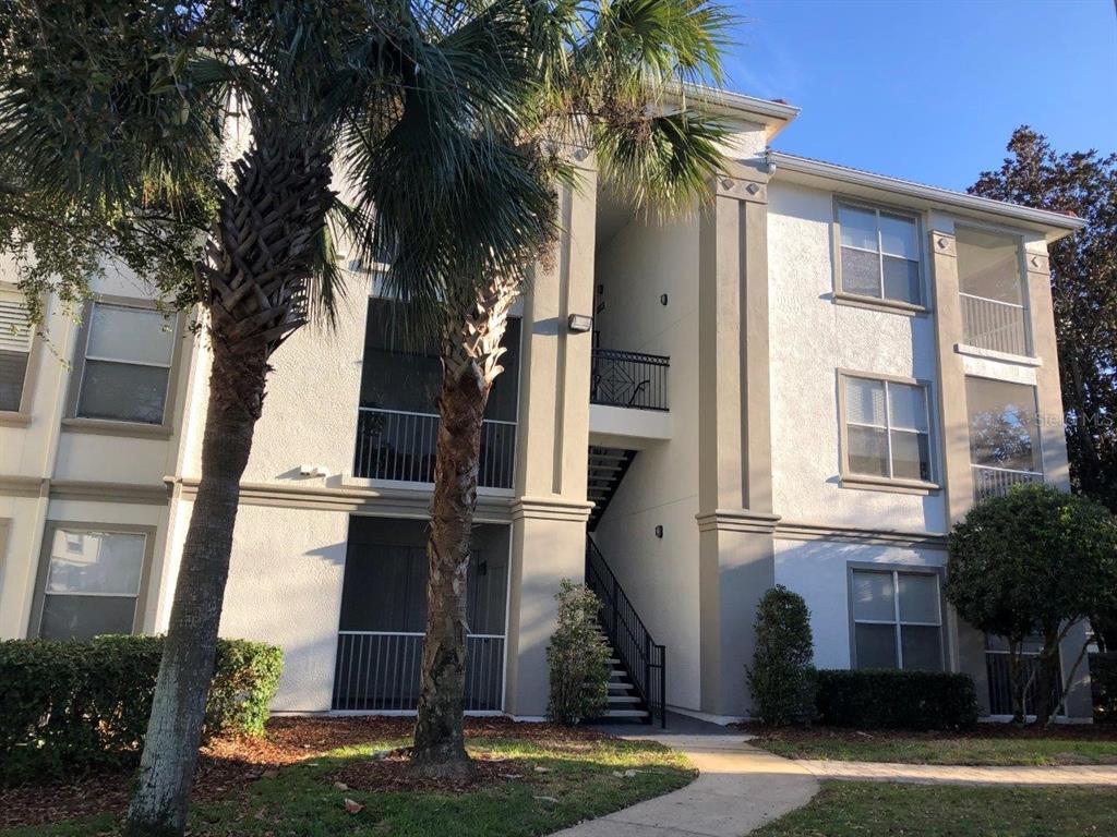 A three-story apartment building exterior with a central staircase, screened balconies, and palm trees — 2627 MAITLAND CROSSING WAY UNIT 304, ORLANDO, FL