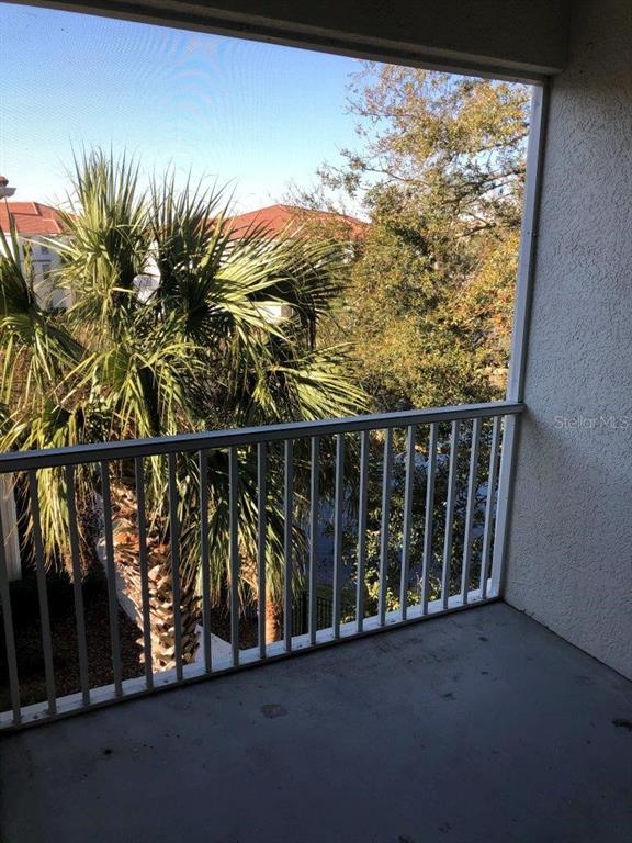 A balcony with a white metal railing overlooks a palm tree and surrounding trees — 2627 MAITLAND CROSSING WAY UNIT 304, ORLANDO, FL