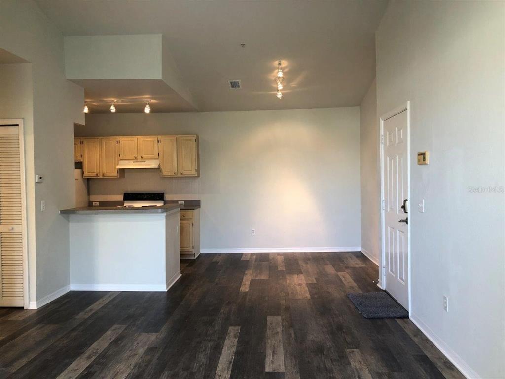 An open-concept kitchen and living area feature light wood cabinets and dark wood-look flooring — 2627 MAITLAND CROSSING WAY UNIT 304, ORLANDO, FL