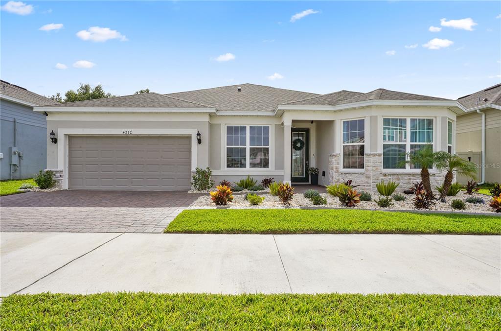 A single-story suburban house with a paved driveway, stone accents, and a landscaped front yard — 4212 WINDING PINES DRIVE, APOPKA, FL