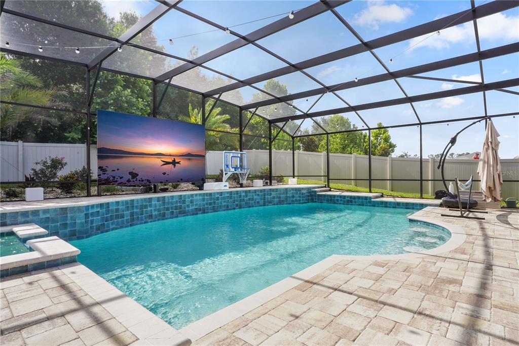 A screened-in swimming pool with blue tile accents and a large outdoor television — 4212 WINDING PINES DRIVE, APOPKA, FL