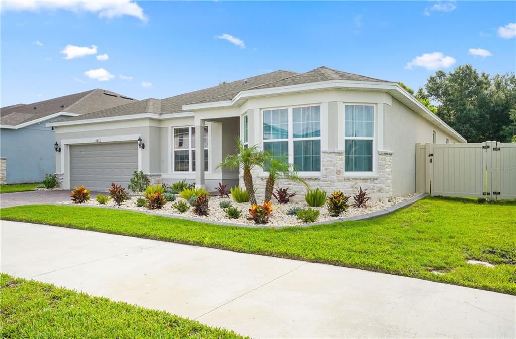 A single-story house with a gray garage, stone accents, and a landscaped front yard — 4212 WINDING PINES DRIVE, APOPKA, FL