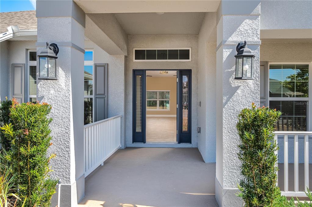 A covered front porch with two pillars, wall-mounted lanterns, and an open front door — 5455 KNIGHTS LANDING DRIVE, LAKELAND, FL