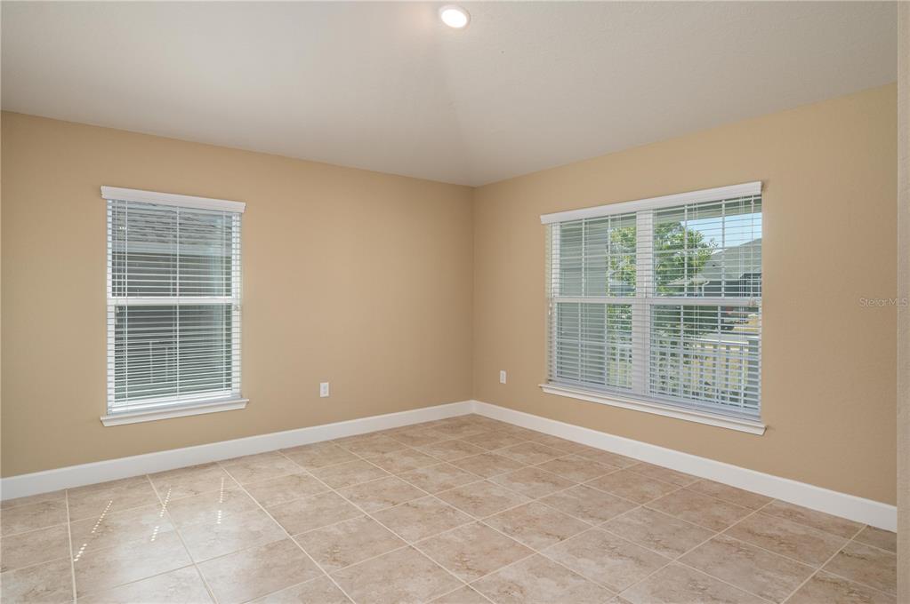 An empty room with beige walls, tile flooring, and two windows with white blinds — 5455 KNIGHTS LANDING DRIVE, LAKELAND, FL
