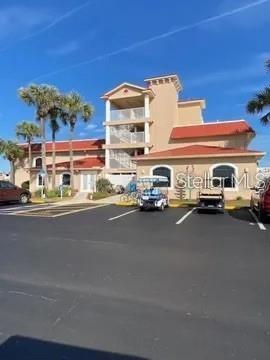 A multi-story tan building with a red roof stands behind a paved parking lot — 96 MERRIMAC DRIVE, FLAGLER BEACH, FL