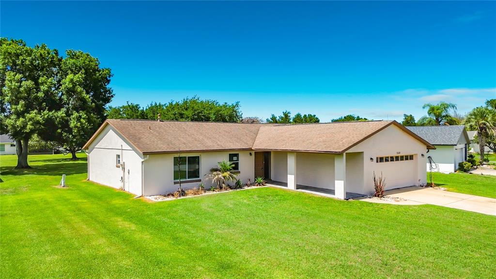 A single-story house with a tan exterior, brown roof, and attached garage sits on grass — 5518 SANDY HILL DRIVE, ORLANDO, FL