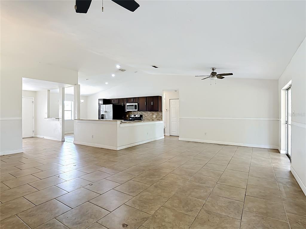 An open-concept living area features tile flooring, a kitchen with dark cabinets, and ceiling fans — 5518 SANDY HILL DRIVE, ORLANDO, FL