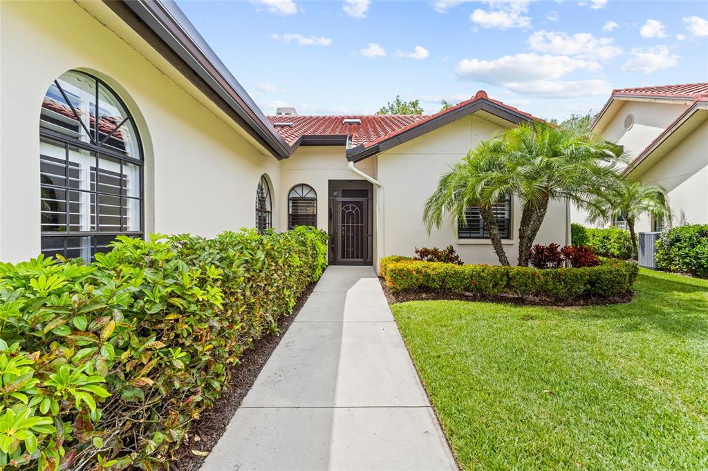 A concrete walkway leads to the front entrance of a house with a tiled roof — 4601 LAS BRISAS LANE, SARASOTA, FL