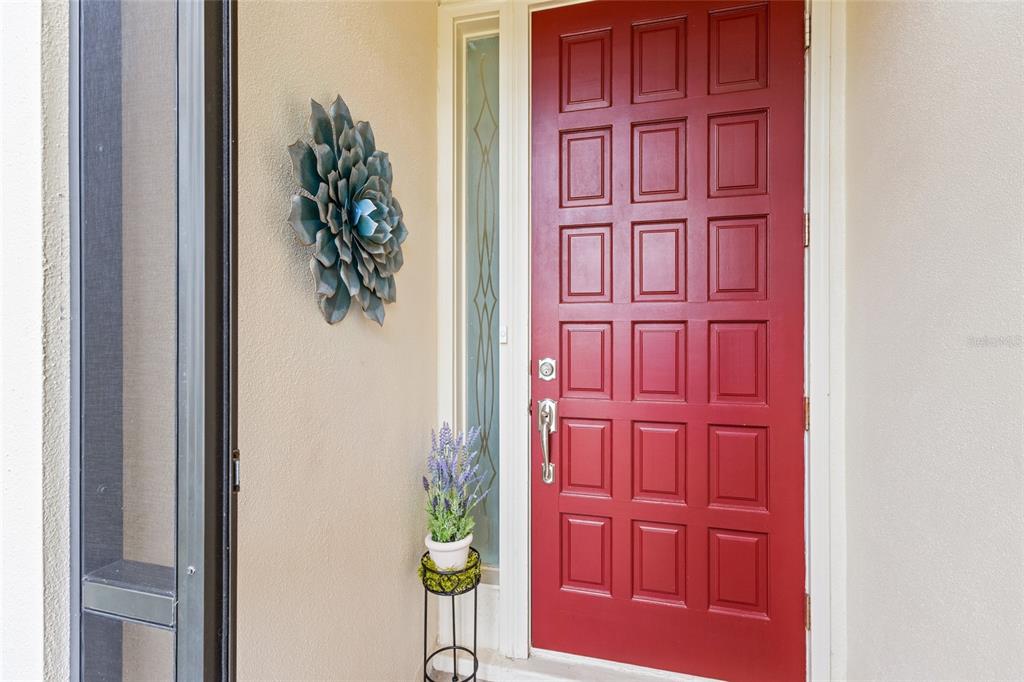 A red front door with a side window and a wall-mounted metal flower decoration — 4601 LAS BRISAS LANE, SARASOTA, FL