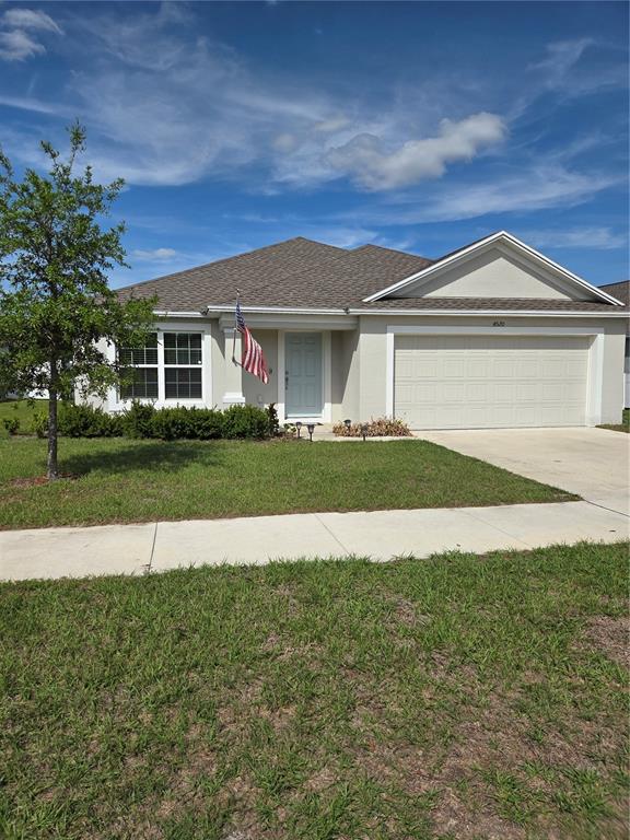 A single-story suburban house with a beige stucco exterior, a two-car garage, and a lawn — 4570 PENKERT PLACE, LAKELAND, FL