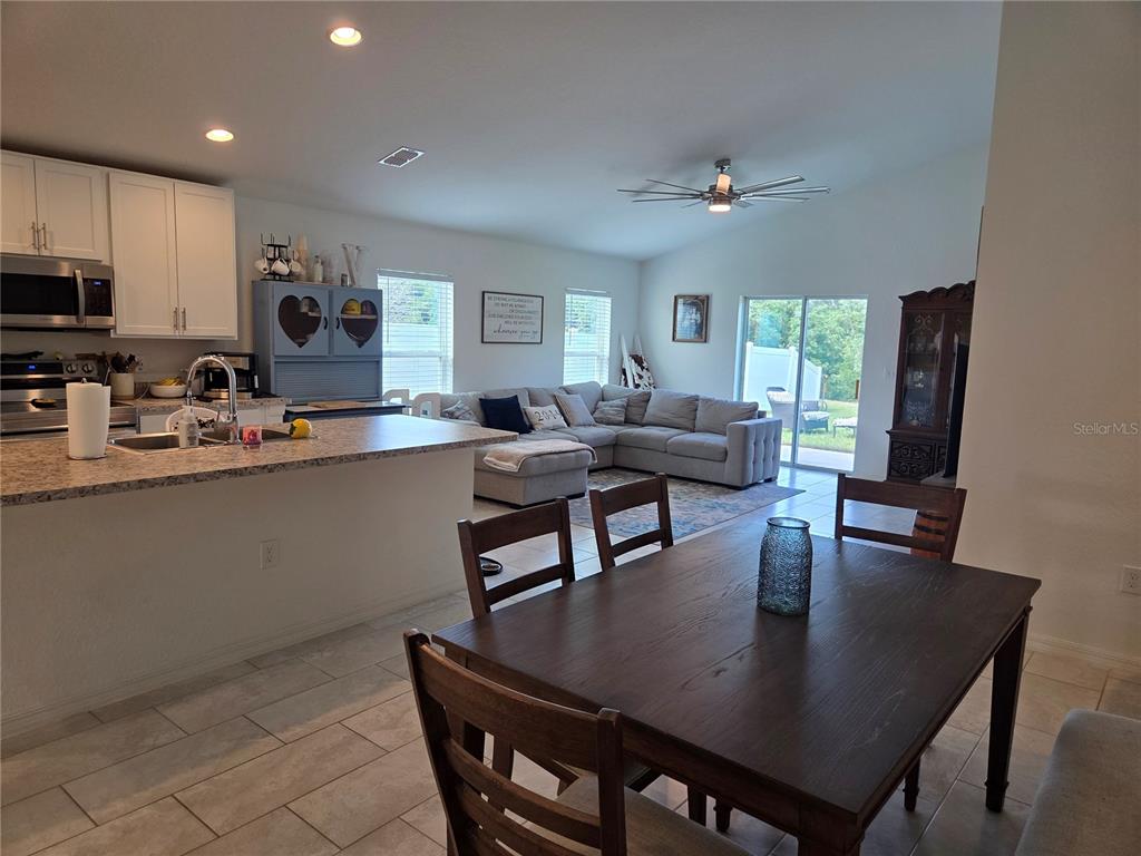 An open-concept kitchen, dining area, and living room feature tile floors and a ceiling fan — 4570 PENKERT PLACE, LAKELAND, FL