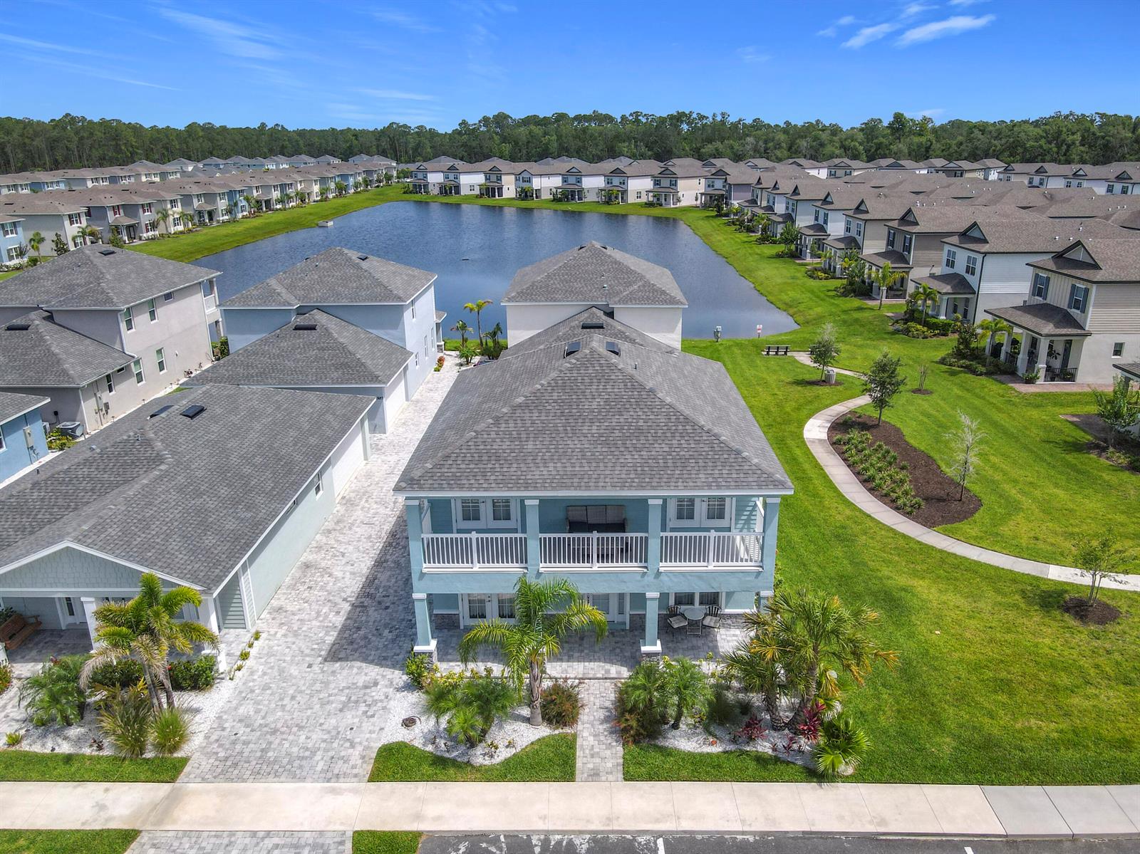 An aerial view shows a light blue two-story house with a balcony facing a lake — 3121 Portofino Boulevard, FL 32168, FL