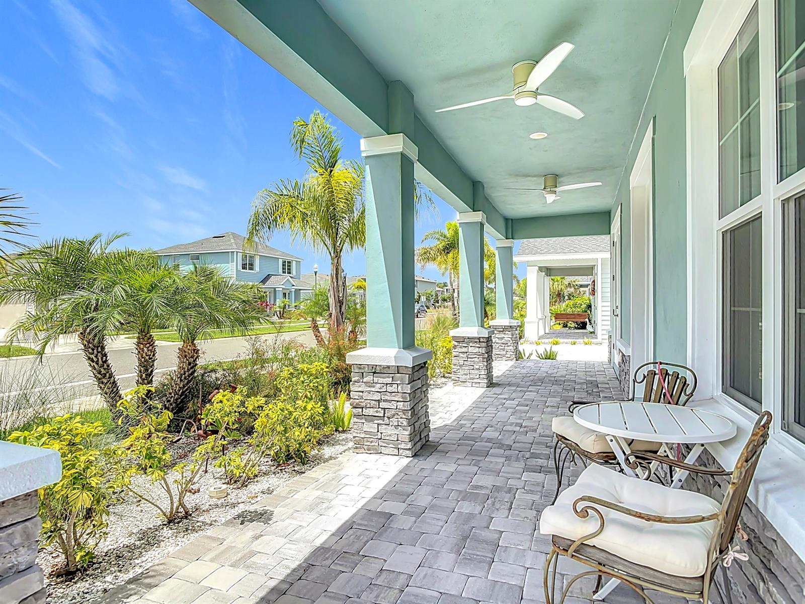 A covered front porch with stone-based columns, a tiled floor, and outdoor seating — 3121 Portofino Boulevard, FL 32168, FL