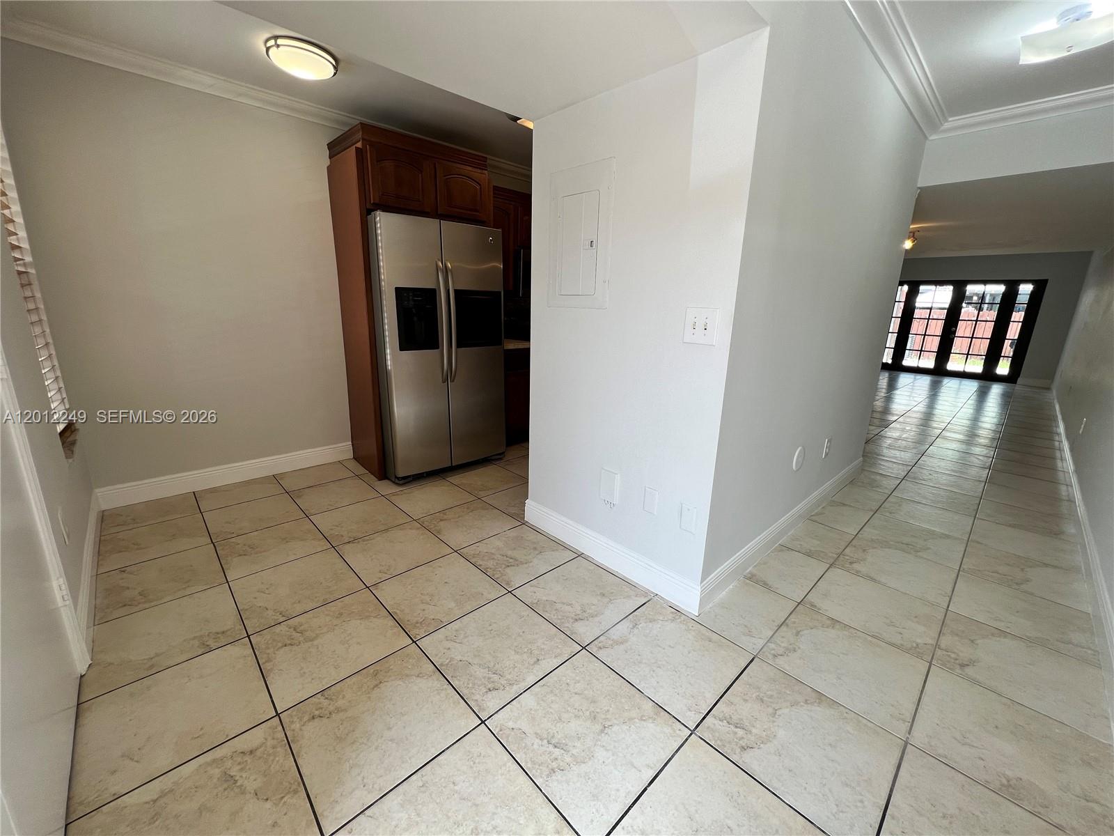 A kitchen area features a stainless steel refrigerator, tile flooring, and a white wall partition — 1187 NW 124th Ave, Miami FL 33182, MIAMI, FL