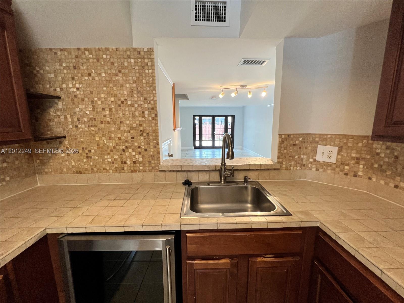 A kitchen features a stainless steel sink, tiled countertops, and a pass-through window — 1187 NW 124th Ave, Miami FL 33182, MIAMI, FL